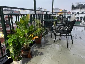 a balcony with a table and chairs and plants at Tranquility Stay in Hanoi
