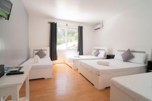 a white room with two beds and a table at Casa Cecilia in El Nido