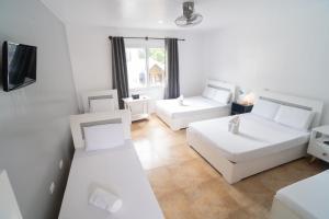 a white room with two white beds and a window at Casa Cecilia in El Nido