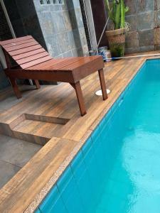 a wooden bench sitting next to a swimming pool at Casa em Freguesia (Jacarepaguá) in Rio de Janeiro