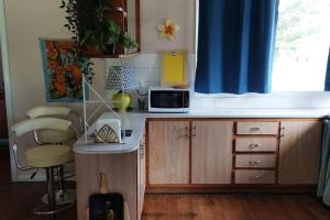 eine Küche mit einer Theke mit einer Mikrowelle und einem Fenster in der Unterkunft Two Pines, whole home in Tullamarine near airport! in Melbourne