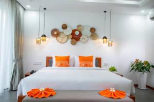 um quarto com uma grande cama branca com almofadas laranja em Wonderland Suites and Resort em Sihanoukville