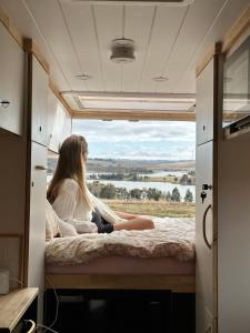 a woman sitting on a bed in a camper van at Two Little Piggies Glamping 