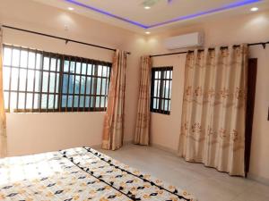 a bedroom with a bed and windows with curtains at Porto-Novo Charme Townhouse in Porto-Novo
