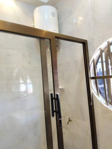a bathroom with a glass shower door and a mirror at Porto-Novo Charme Townhouse in Porto-Novo