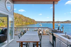 a deck with a table and a view of the water at The Boathouse in Daleys Point