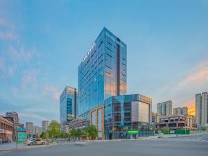 ein hohes Glasgebäude mitten in einer Stadt in der Unterkunft YueSen Yizhi Hotel in Dazhou