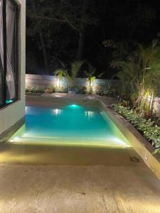 a swimming pool with lights in a yard at night at Palm 3Bhk Villa Alibaug in Alībāg