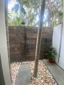 a bathroom with a shower with a stone wall at Palm 3Bhk Villa Alibaug in Alībāg