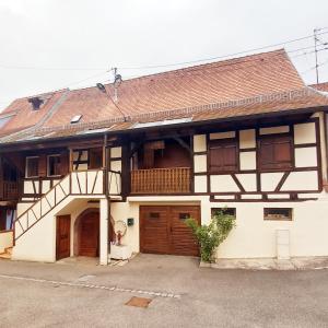 uma casa antiga com portas de madeira e um telhado em La Valériane em Kintzheim