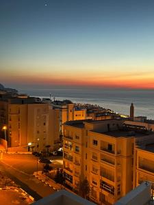 un coucher de soleil sur une ville avec des bâtiments et l'océan dans l'établissement Welcome to THE VIEW!, à Al Hoceïma