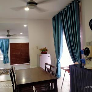 comedor con mesa y cortinas azules en Sri Manik Guest House Tanjung Karang, en Tanjung Karang