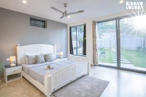 a bedroom with a white bed and a large window at StayVista at Walk in the Woods in Solan