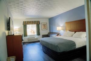 a bedroom with a bed and a chair and a window at Royal Inn & Suites in Akron +22 photos