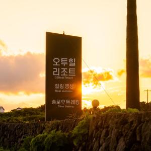 a sign with the sun setting in the background at O2Heal resort in Jeju