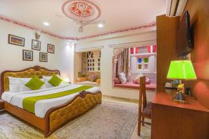 a bedroom with a bed and a desk and a television at Royal Rafahiya Haveli - LAKE FACING in Udaipur