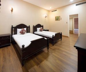 Hidden Mansions Saigon Resort في مدينة هوشي منه: سريرين في غرفة ذات أرضيات خشبية