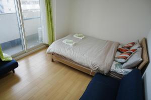 1 cama y 1 sofá en una habitación con ventana en Orange House 702 en Osaka