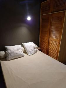 ein Bett mit weißer Bettwäsche und Kissen darauf in der Unterkunft Petit chalet individuel à Font-romeu in Font Romeu Odeillo Via