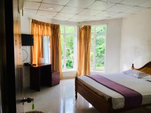 ein Schlafzimmer mit einem Bett und einem großen Fenster in der Unterkunft Diyaluma Falls Inn in Koslanda