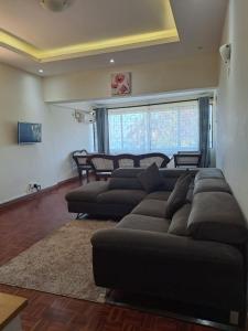 a living room with a large brown couch and chairs at PALM TERRACE HOMESTAY NYALI - On samaki lane in Mombasa