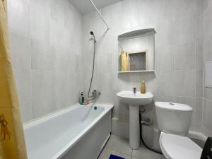 uma casa de banho com um lavatório, um WC e uma banheira em Уютная и новая квартира в Костанае em Qostanay