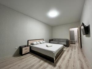 um quarto com uma cama e uma televisão em Уютная и новая квартира в Костанае em Qostanay