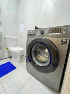 uma máquina de lavar roupa na casa de banho com WC em Уютная и новая квартира в Костанае em Qostanay