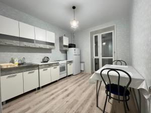 uma cozinha com armários brancos e uma mesa com cadeiras em Уютная и новая квартира в Костанае em Qostanay