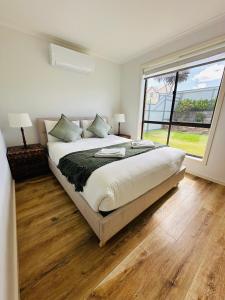 a bedroom with a large bed and a large window at Kangaroo Island Homestays in Kingscote