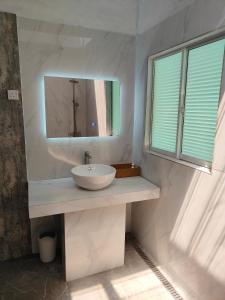 a white bathroom with a sink and a mirror at GreenHouse EcoLodge in Mantanani Island 