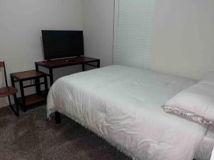 a bedroom with a white bed and a television at Everything you need to call home in Norman