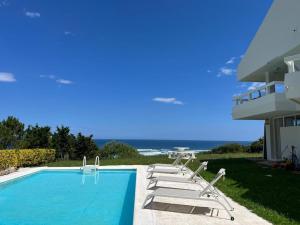 a swimming pool with lounge chairs next to a house at Impresionante villa sobre el mar en el mismo Comillas in Comillas