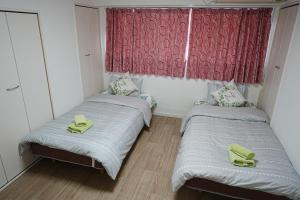 Habitación pequeña con 2 camas individuales y zapatillas amarillas. en Orange House 701, en Osaka