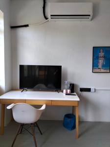 uma secretária com uma cadeira branca e um monitor de computador em le melur guest house em George Town