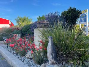 eine Statue eines Vogels in einem Garten mit Blumen in der Unterkunft ASURE Ambassador Motor Lodge in Oamaru