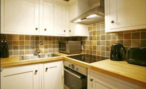 a kitchen with white cabinets and a sink at Central London Rooms in London