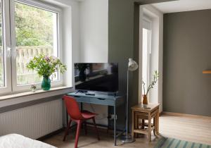 um quarto com uma secretária, uma televisão e uma janela em Central apartment with Terrace em Duisburg