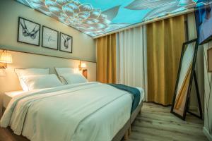 um quarto de hotel com uma cama e um quadro no tecto em La Sublime Love House em Briey