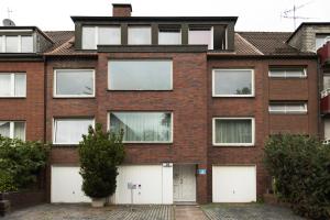 uma antiga casa de tijolos com portas de garagem brancas em Central apartment with Terrace em Duisburg