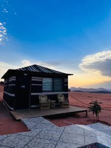 una cabaña en medio del desierto con dos sillas en Wadi Rum - Deluxe Tent, en Wadi Rum
