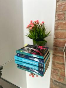 a stack of books on a table with a vase of flowers at Central Station Apartment in Cluj-Napoca