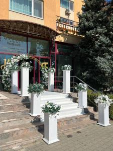 ein Satz weißer Säulen mit Blumen vor einem Gebäude in der Unterkunft Hotel Flora in Drobeta-Turnu Severin