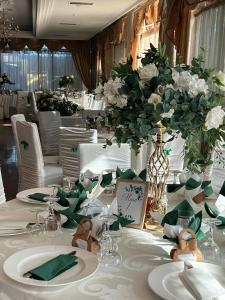 a table with white plates and flowers on it at Hotel Flora in Drobeta-Turnu Severin