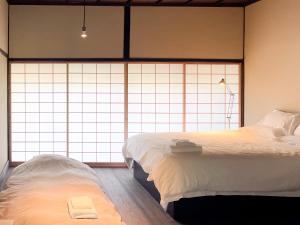 2 Betten in einem Zimmer mit großen Fenstern in der Unterkunft Akizuki Kayabuki Kominka in Asakura