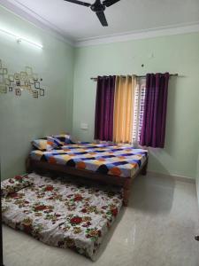 a bedroom with a bed and a comforter on the floor at Galaxy Villa's Homestay 8431o31389 in Mysore