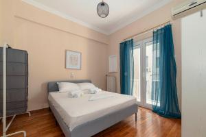 a bedroom with a bed with blue curtains and a window at Spacious 2bd apartment next to Athens Archeological museum in Athens