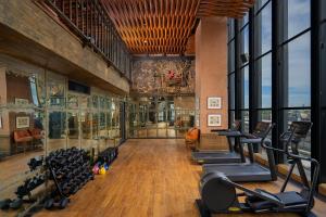 a gym with lots of exercise equipment and windows at The Orient Jakarta, a Royal Hideaway Hotel in Jakarta