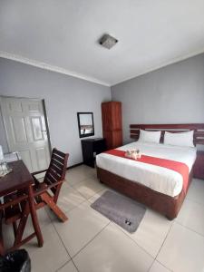 um quarto com uma cama, uma mesa e uma cadeira em Universe GuestHouse em Kasane