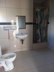 a bathroom with a toilet and a sink at Universe GuestHouse in Kasane